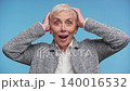 Surprised senior woman holding her head on Blue Background 140016532