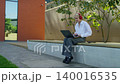 Woman Scrolling on Laptop Outdoors 140016535