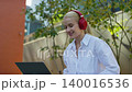 Young woman with headphones using laptop outdoors 140016536