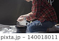 Woman attaches paint roller sleeve to handle beside tray, bucket, and protective sheet. DIY painting, renovation, and decorating concept 140018011