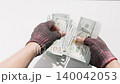 Homeless person counts a stack of US dollar bills against a plain white background. 140042053