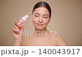 Young woman shows off a bottle with a foam dispenser for washing 140043917