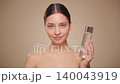 Smiling woman holds bottle with cosmetic tonic 140043919