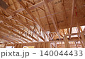 Workers are installing wooden beams to build roof frame at construction site 140044433