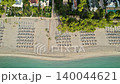 Beach has many chairs lined up under trees near residences pool, at coast Majorca Balearic Islands Spain 140044621
