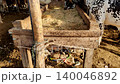 cow resting on wooden plank and eating hay while flies surround it at dusty lyari cattle market before eid ul adha 140046892