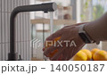 Hands wash orange under running water from kitchen faucet. Concept of fruit cleaning and food hygiene 140050187