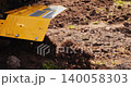 Close up view of a motor cultivator tilling the earth with its blades, preparing the land for planting crops and turning the soil in the garden for the new farming season. 140058303