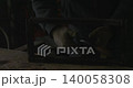 Industrial welder with protective gloves connecting metal profile pipes in a workshop, creating bright flashes of light, sparks, and smoke during the manufacturing process in a factor. 140058308