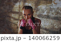 Young athletic woman with braided hair throwing punch wearing pink bandages during intense training session in gym with focused expression 140066259