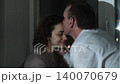 A man and a woman look at each other lovingly while sitting by the window at night 140070679