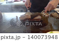 Chef preparing grilled meat on hot teppanyaki grill with spatula 140073948