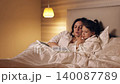 Loving mother reading a fascinating bedtime story to her little daughter. The girl listens carefully while lying comfortably in bed 140087789