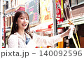一位女士一邊散步一邊享用美食 140092596