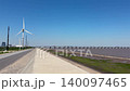 A video showcasing the clean energy of wind turbines on a coastal embankment road, tidal flats, and the blue sky. 140097465