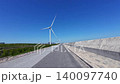 Bicycle POV ride: Action camera video of wind turbines and blue sky on a coastal embankment road. 140097740