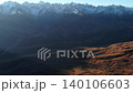 Aerial view of barren red-brown mountains with distant snow-capped peaks under clear daylight . Media 140106603