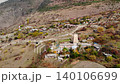 Aerial view of a rural mountain village with scattered houses and a tower . Media 140106699
