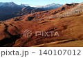 Aerial view of barren red-brown mountains with distant snow-capped peaks under clear daylight . Media 140107012