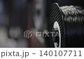 Black 3D printer filament spool feeding plastic material during additive manufacturing. Industrial production process for prototyping, engineering and product development. 140107711