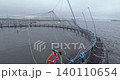 Large fish farm in the water with nets under cloudy sky as background angle shot 140110654