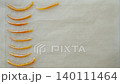 Hand arranges candied orange peel strips on parchment paper. Concept of homemade sweets and citrus dessert 140111464