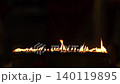 Rows of warm candle flames in a dark temple setting create a sacred visual composition with glowing light, soft smoke, and peaceful Buddhist worship atmosphere. 140119895