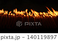 Rows of warm candle flames in a dark temple setting create a sacred visual composition with glowing light, soft smoke, and peaceful Buddhist worship atmosphere. 140119897