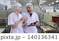 Two inspectors examining canned food and quality control in factory, food industry production line. 140136341
