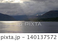 Dramatic drone view over Loch Linnhe in the afternoon, showing sunbeams bursting through heavy storm clouds to illuminate the Scottish Highland shoreline 140137572