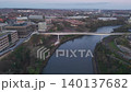 High-angle aerial drone shot flying backward from the modern Keel Crossing to reveal the historic Monkwearmouth Railway Bridge and Wearmouth Bridge at dawn. 140137682
