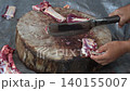 Butcher cuttingButcher cutting raw meat on a wooden chopping block	 raw meat on a wooden chopping block	 140155007