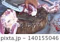 Butcher cuttinButcher cutting raw fresh meat on a wooden board on the ground	g raw fresh meat on a wooden board on the ground	 140155046