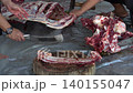 Butcher cuttinButcher cutting raw fresh meat on a wooden board on the ground	g raw fresh meat on a wooden board on the ground	 140155047