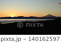 At Kugenuma Beach, a sunset scene with surfers and people strolling, and the silhouette of Mount Fuji. 140162597