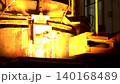 Heavy industrial plant where molten material flows from a furnace into molds, showcasing intense heat, and large-scale production, real-time footage  140168489