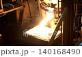 Heavy industrial plant where molten material flows from a furnace into molds, showcasing intense heat, and large-scale production, real-time footage  140168490