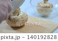 Fresh white mushrooms are sliced on a wooden cutting board, with a bowl of whole mushrooms visible in the background, highlighting kitchen preparation 140192828