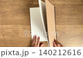 一隻孩子的手打開一本大筆記本，一隻成年人的手輕輕調整筆記本的位置。 （4K無聲影片） 140212616