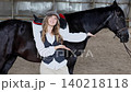Young woman confidently posing with black horse indoors 140218118