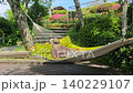 A woman resting in a hammock in a garden with fresh greenery. 140229107