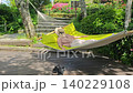 A woman resting in a hammock in a garden with fresh greenery. 140229108