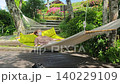 A woman resting in a hammock in a garden with fresh greenery. 140229109