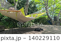 A woman resting in a hammock in a garden with fresh greenery. 140229110