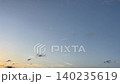 In the twilight sky, a distant airplane creates a contrail. 140235619