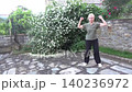 A body twist exercise to strengthen the back and pelvic muscles. A woman twists her body with bent arms and squats with her legs bent. A simple exercise for home or outdoors 140236972