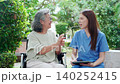 Asian woman nurse examining senior patient arm for physical therapy and record document on tablet. 140252415