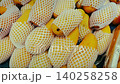 Yellow mangoes covered in mesh netting are arranged in a market display, highlighting their freshness and appealing appearance in a fruit stall 140258258