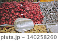 Vibrant assortment of dried fruits and nuts in a market, showcasing red raspberries, yellow apricots, and green pistachios with a silver scoop 140258260