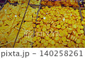 Assorted yellow cookies and snacks fill transparent containers, highlighting diverse shapes and textures in a lively food market environment 140258261